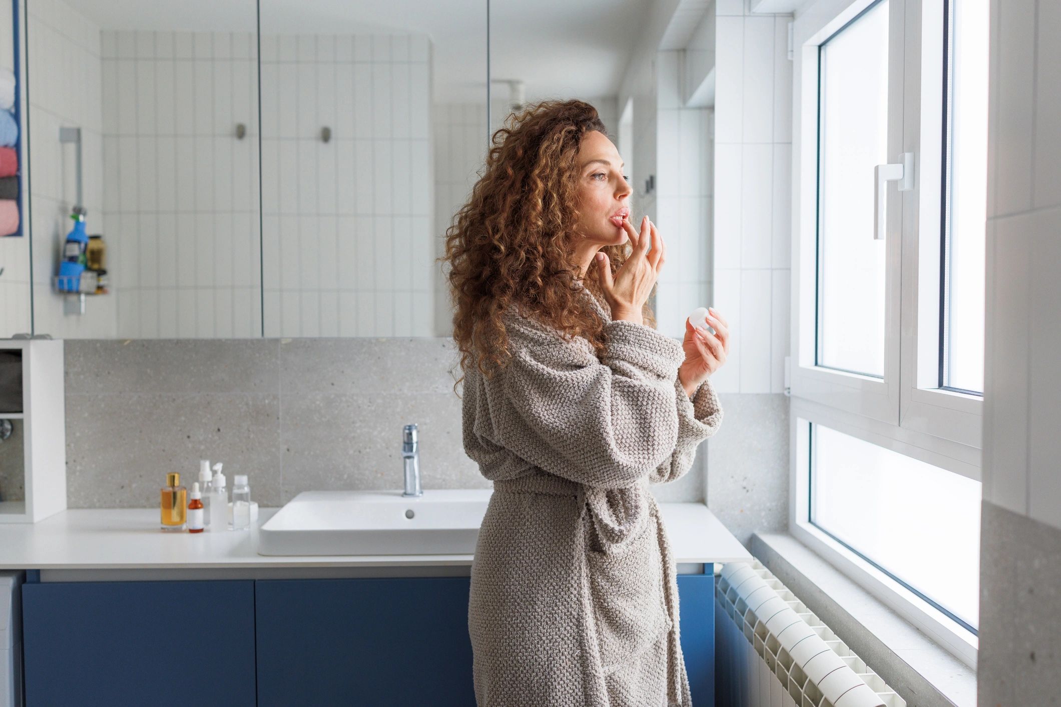 Woman applying lip balm during a beauty routine