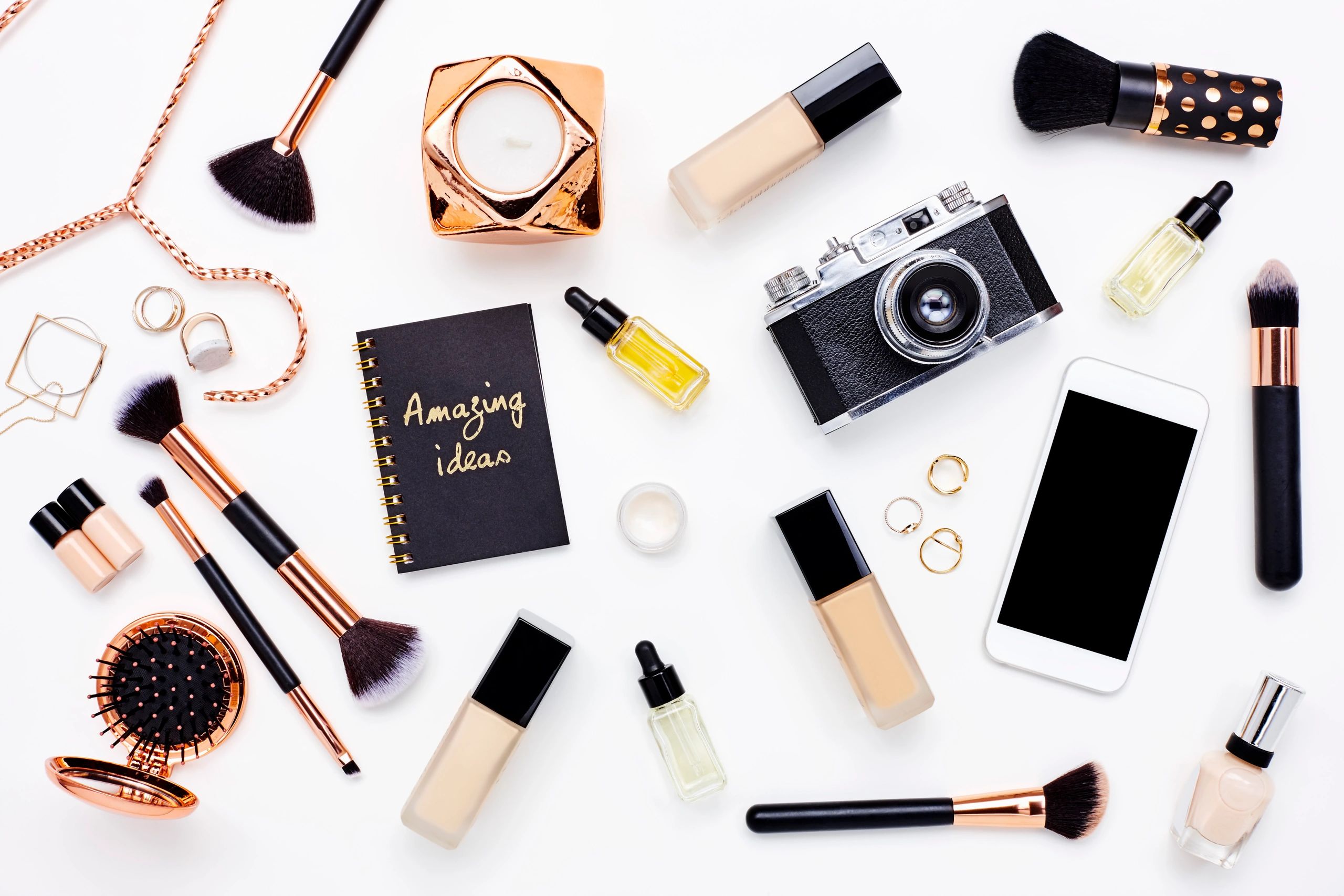 Flat lay of beauty products and accessories on a white desk